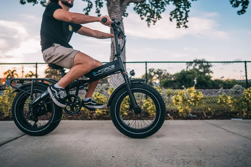 A man leisurely rides an electric bike on a sunny day in the city street