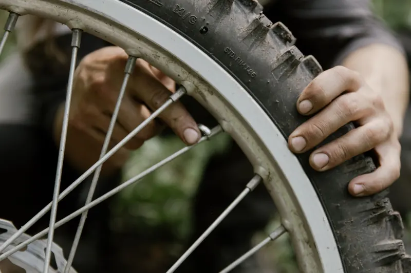 Mechanic using hands to repair a bicycle tire in an outdoor setting