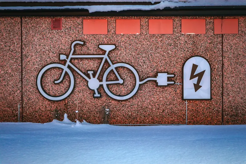 Electric bike charging graphic on a snowy urban wall, promoting renewable energy