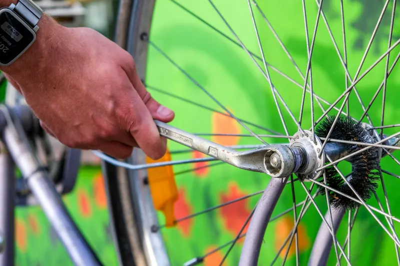 Close-up of a man repairing a bicycle wheel with a wrench. Focus on hand and spokes