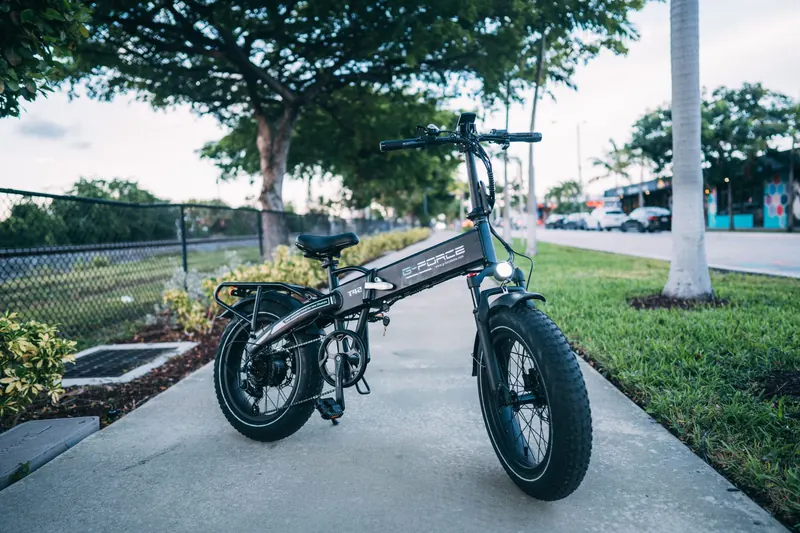Sleek electric bike parked on a city sidewalk surrounded by greenery